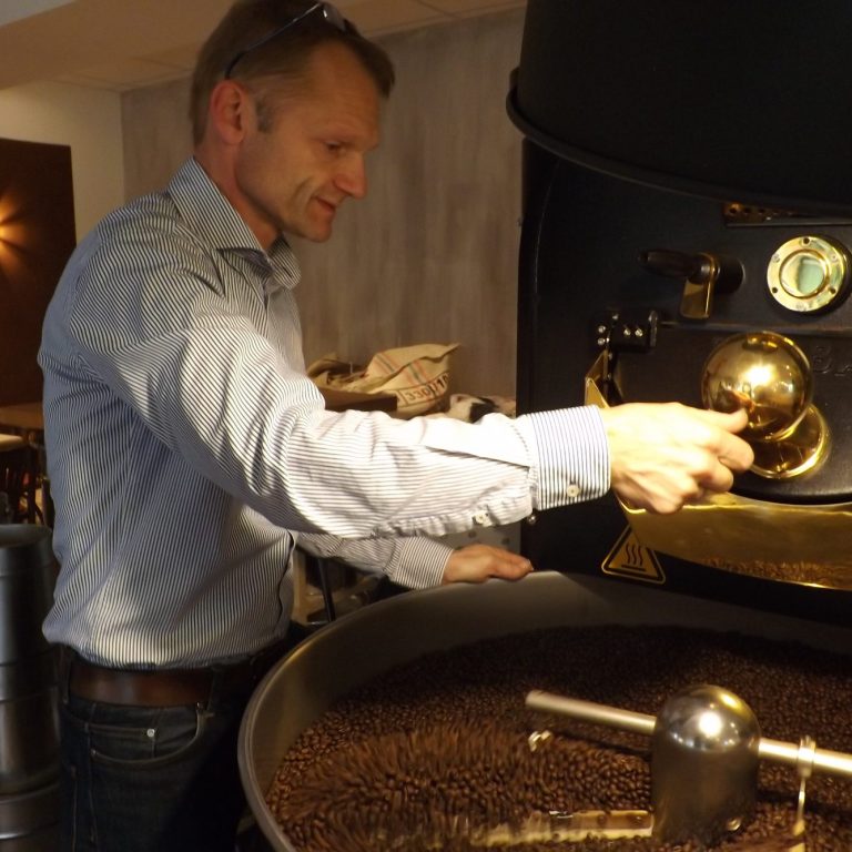 Mann steuert eine Kaffeeröstanlage und überwacht den Röstprozess.